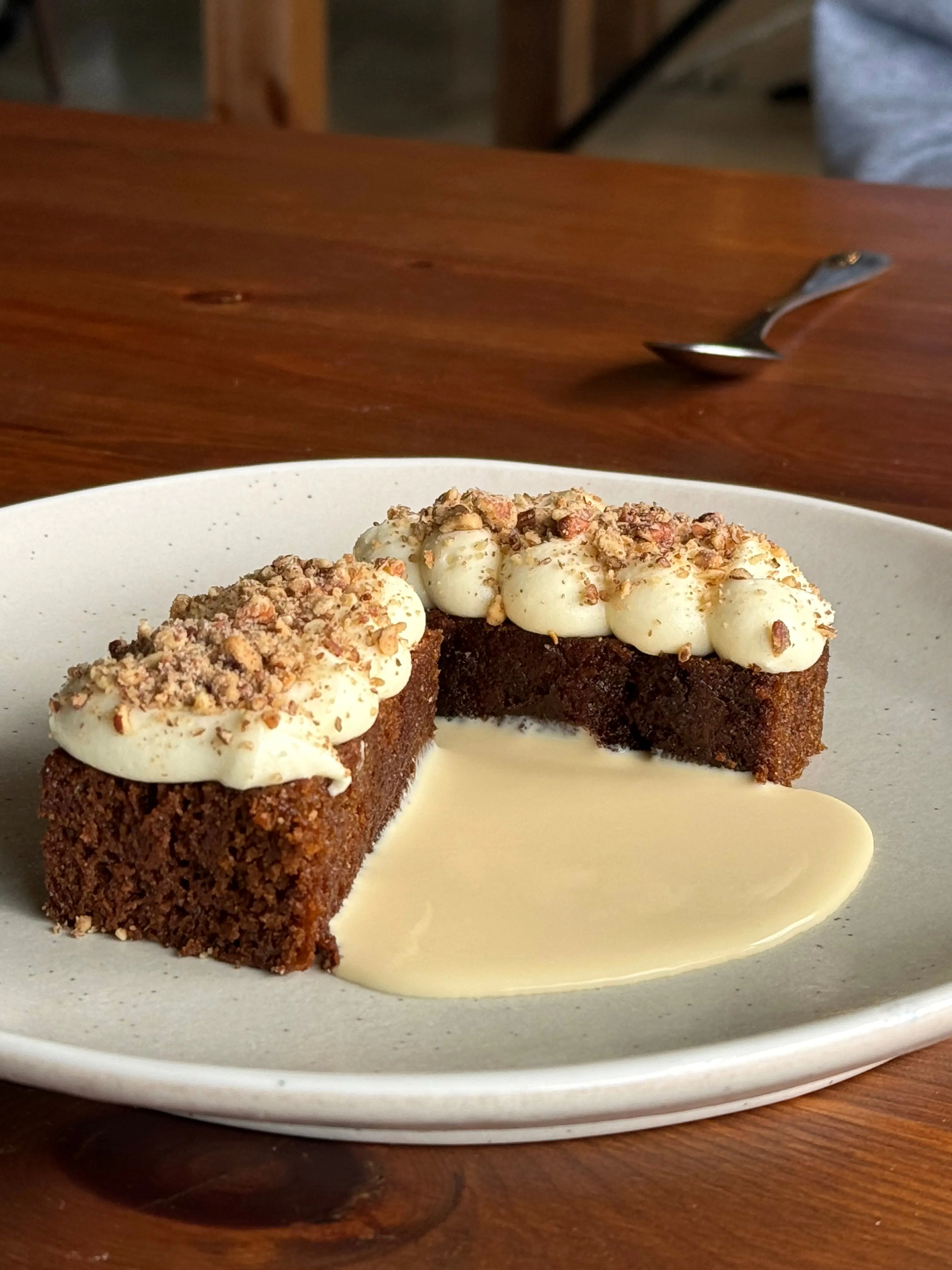 A slice of spiced cake with cultured cream, candied nuts and pouring custard at Frida's Field