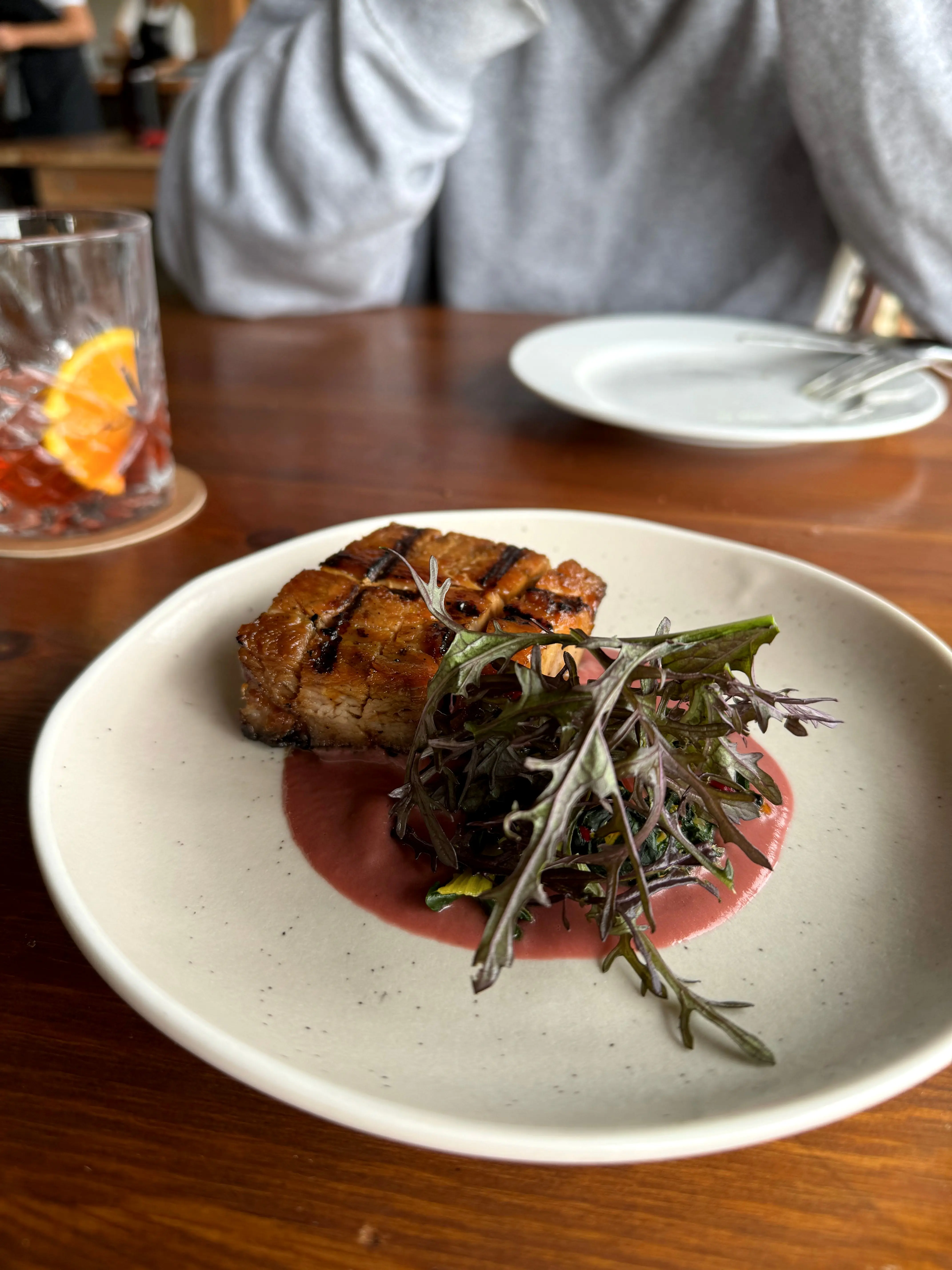 A slow-grilled pork main with leaves and a beetroot sauce on a speckled plate at Frida's Field