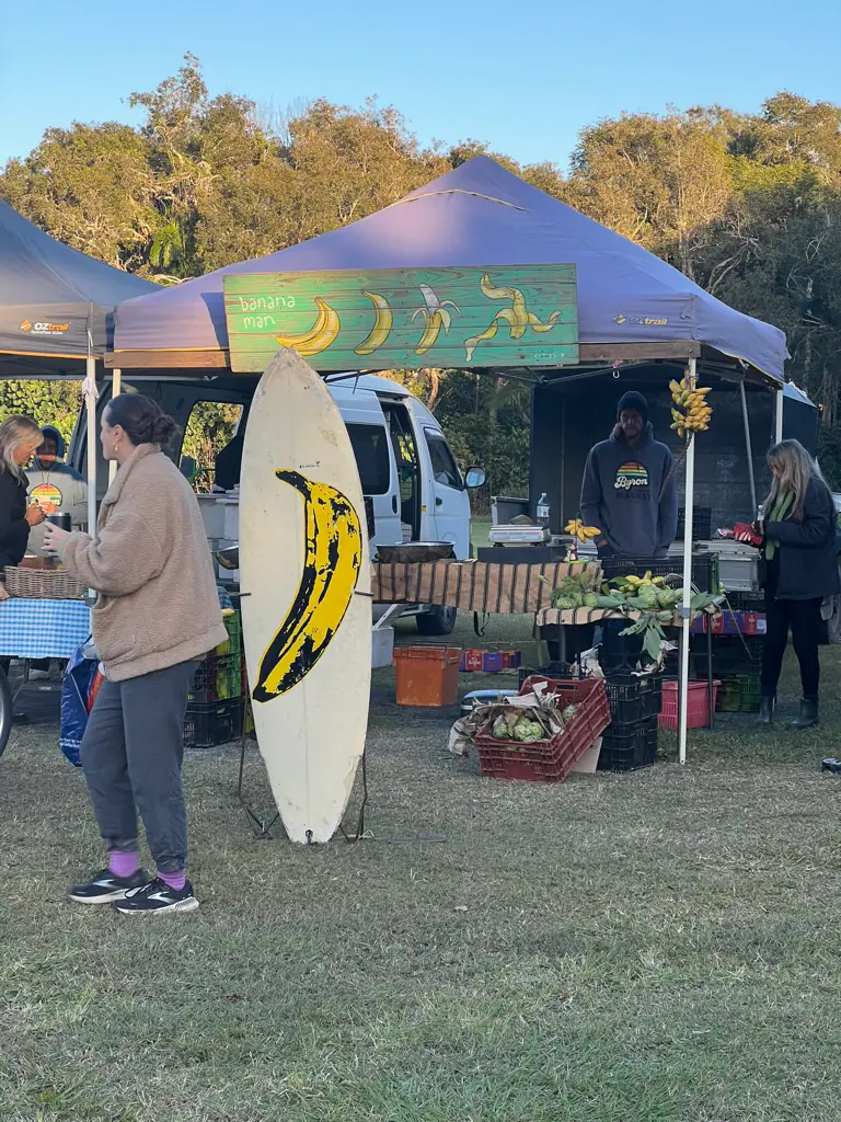 The Byron Bay Bananaman stall with a hand-painted 'banana man' sign and a surfboard painted with a banana propped out the front