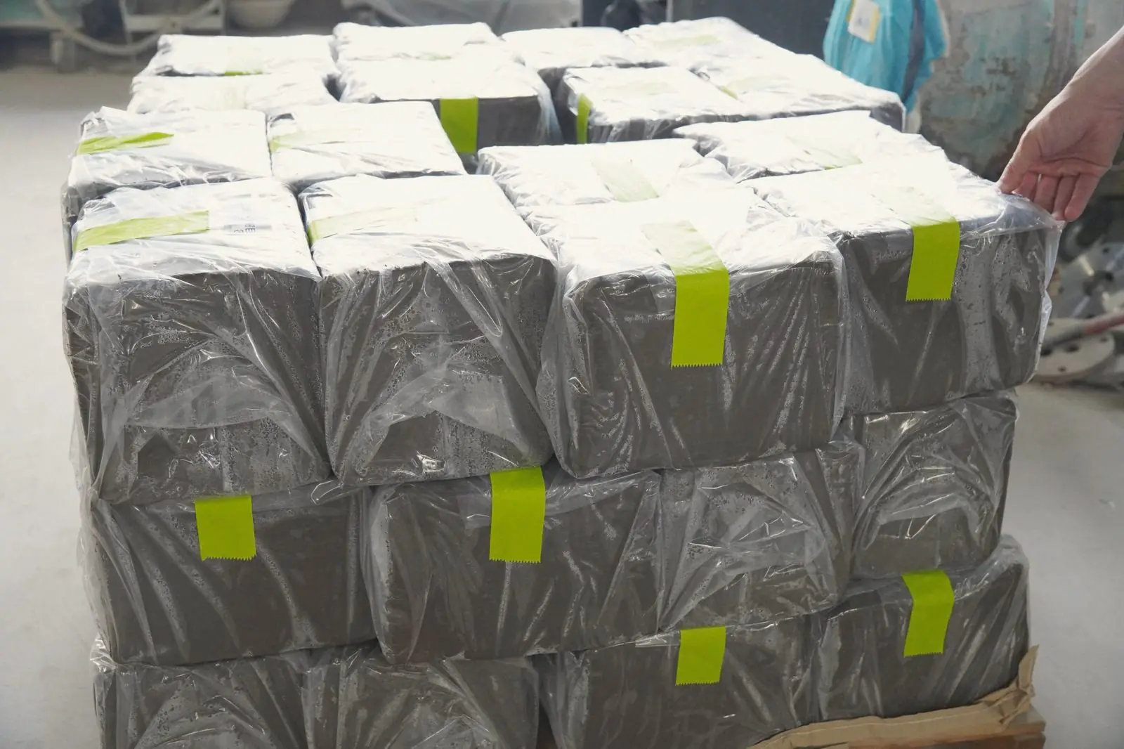 Blocks of grey Shigaraki clay wrapped in plastic and stacked on a pallet.