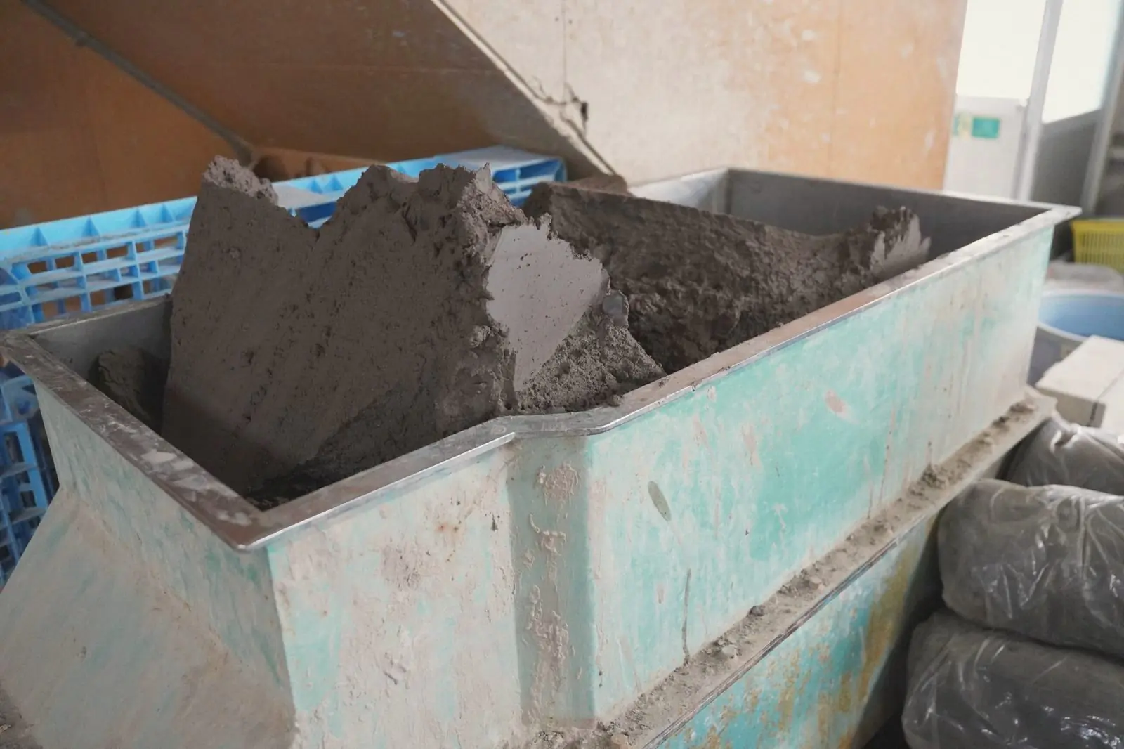 Dark clay being prepared in a large metal hopper at the workshop.