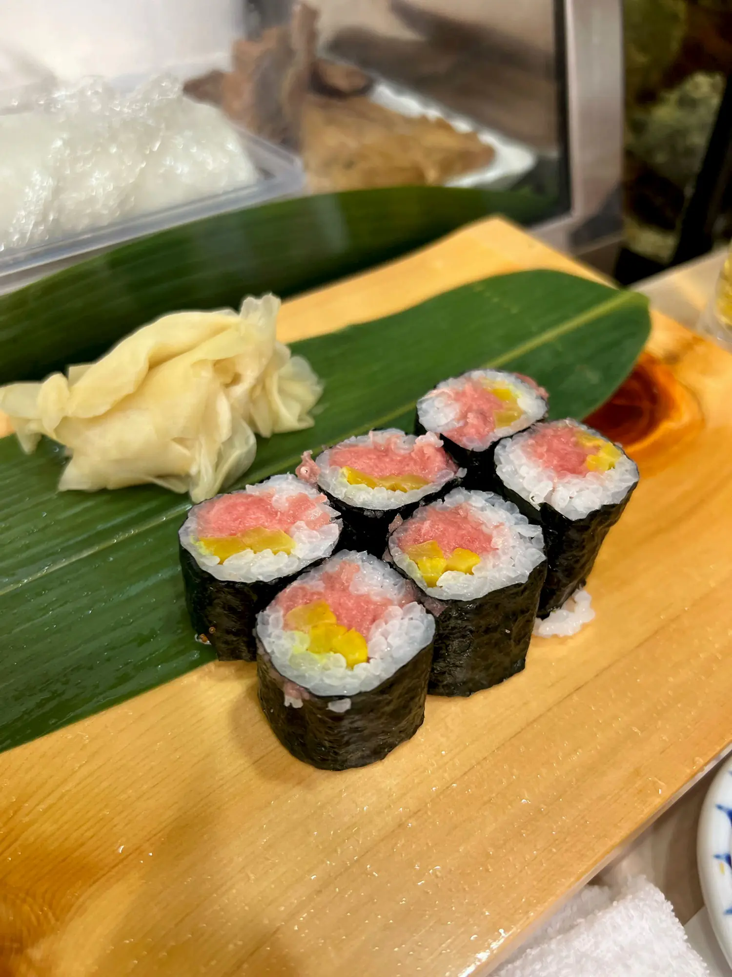Negitoro maki sushi rolls on a bamboo leaf, with pickled ginger on the side