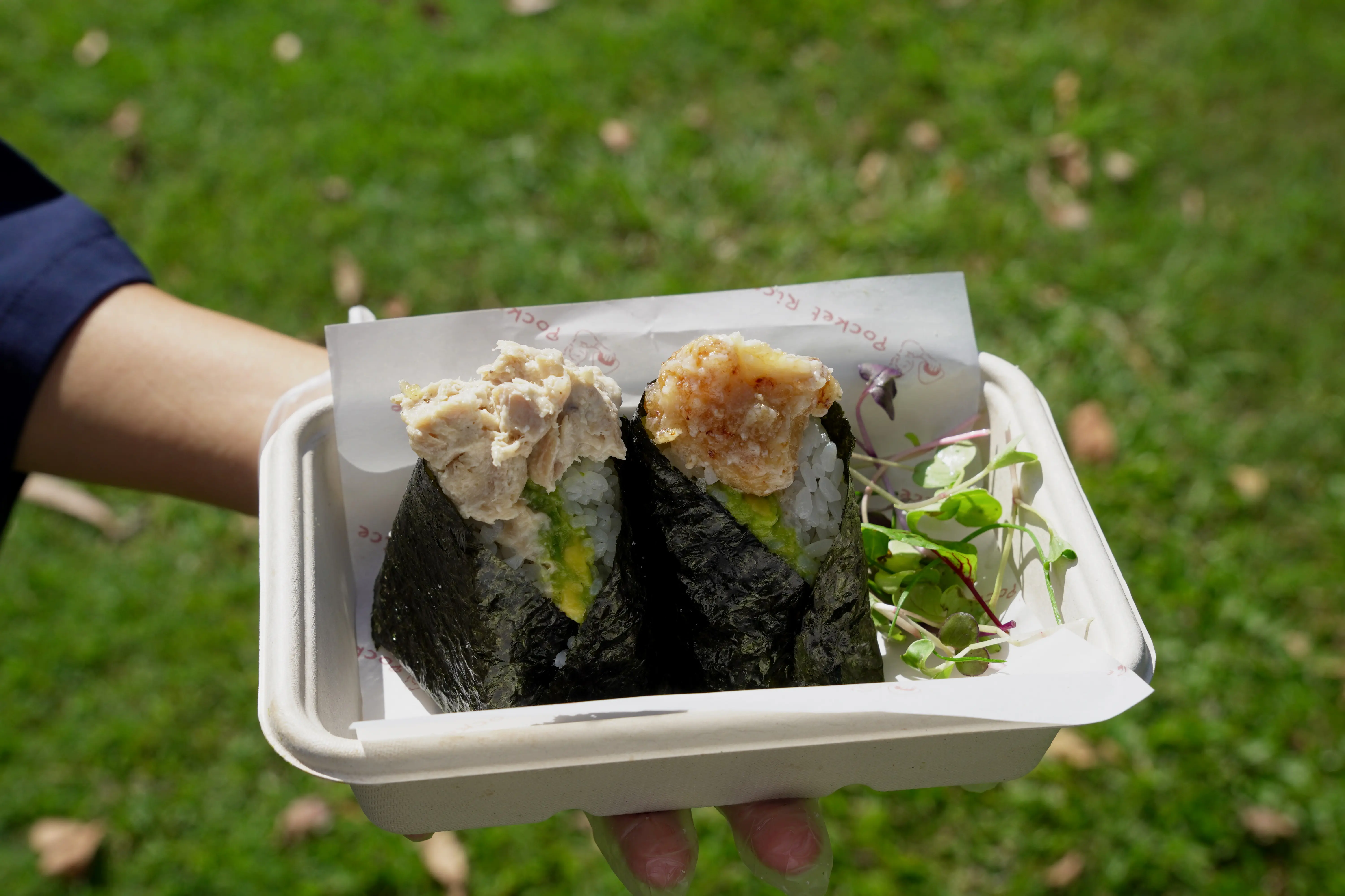 A pair of Pocket Rice onigiri — tuna mayo and karaage chicken — held in a branded takeaway box at a Byron Bay market