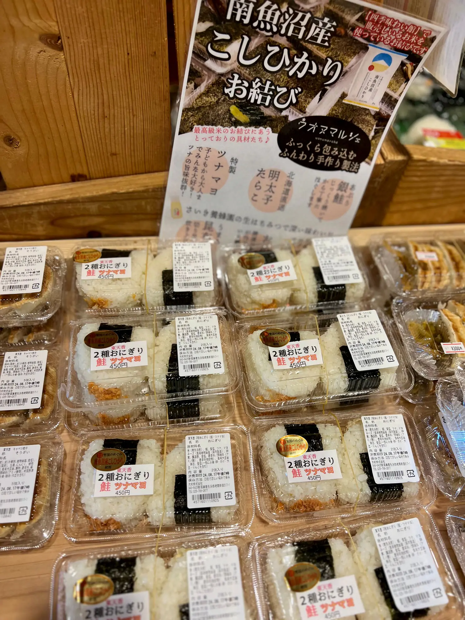 Packaged onigiri stacked on a Japanese shop shelf below a Koshihikari rice display